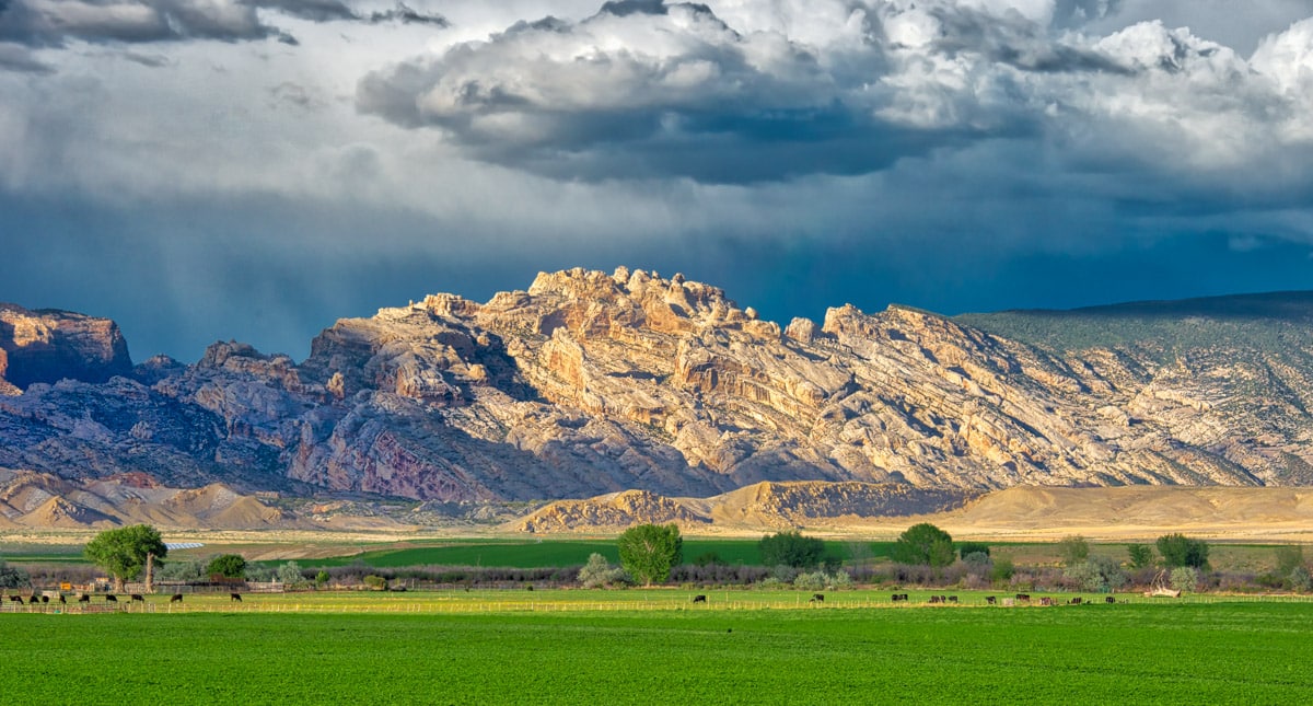 The dark rain clouds and virga serve as a backdrop to the magnificent Split Mountain and the ranch land in the foreground. This was taken along the entrance road to Dinosaur National Monument in Utah.